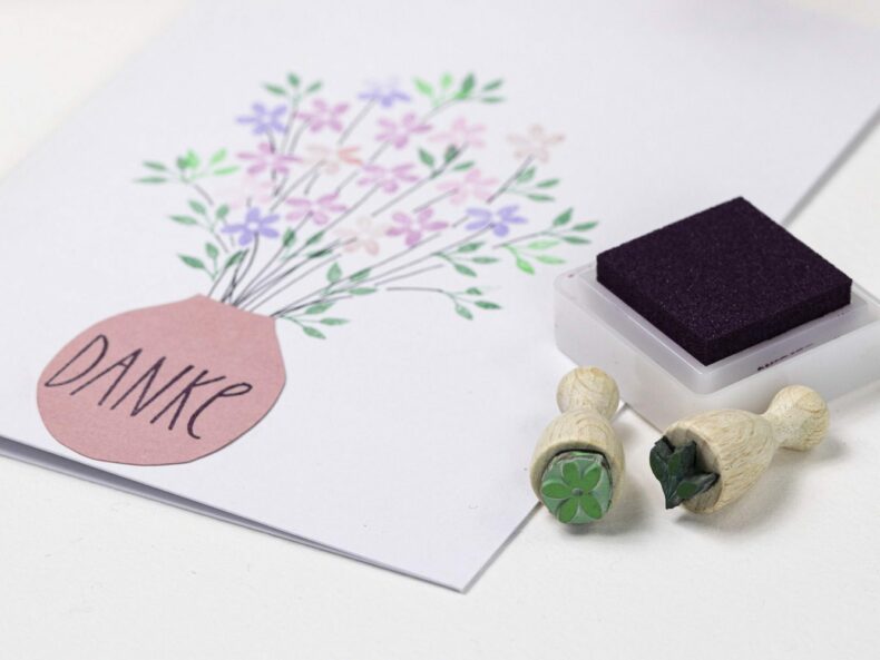 Zwei Ministempel, ein kleines Stempelkissen in dunkel lila und eine Karte mit Blumenstrauß
