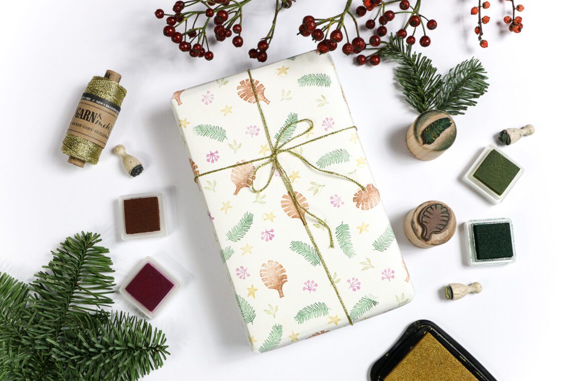 Weihnachtliches Geschenkpapier mit Stempeln selber machen mit den Motivstempeln Tannenzweig, Zapfen, Ministempeln und goldenem Bäckergarn