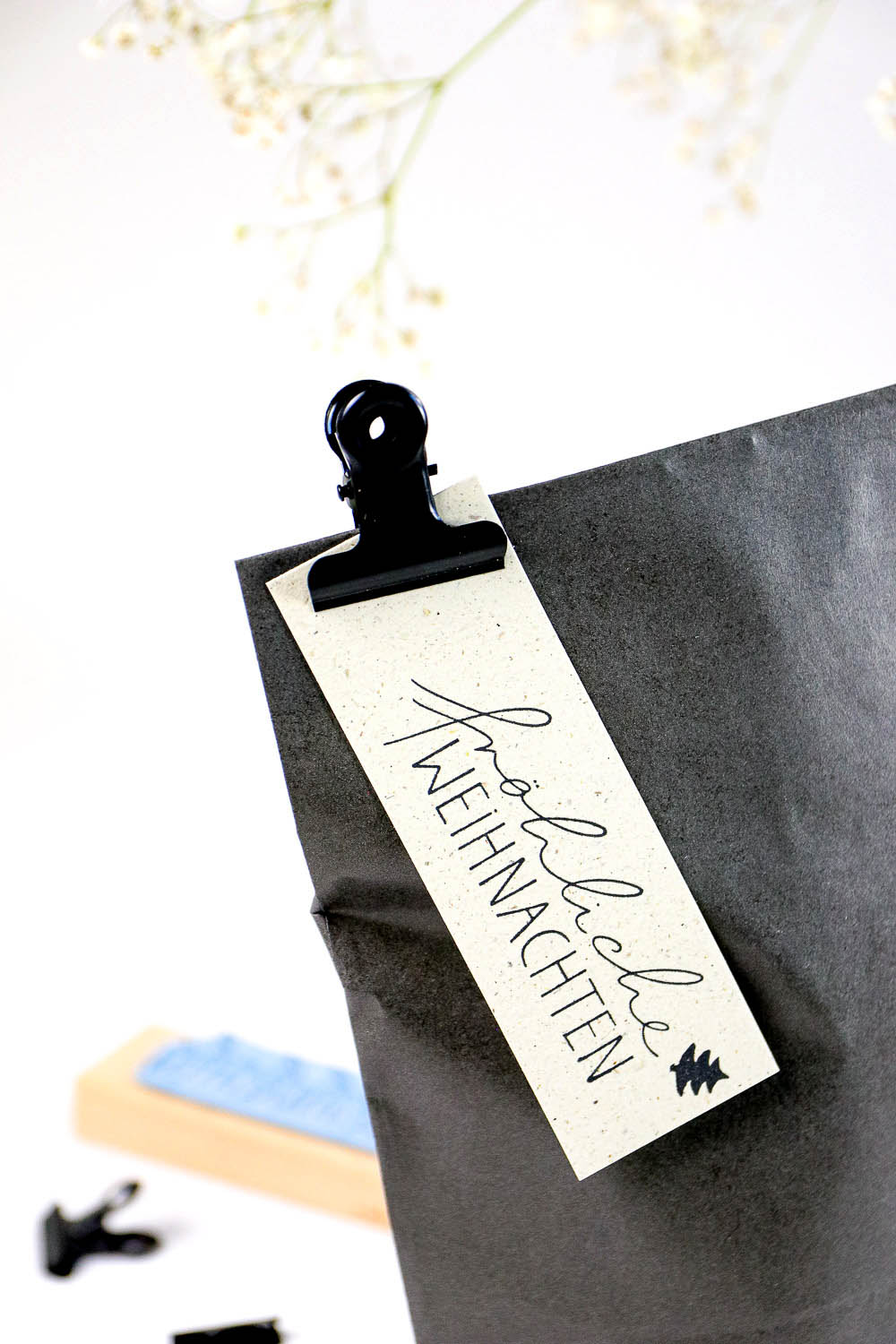 Textstempel fröhliche Weihnachten auf Geschenkanhänger gestempelt und an Geschenküte befestigt